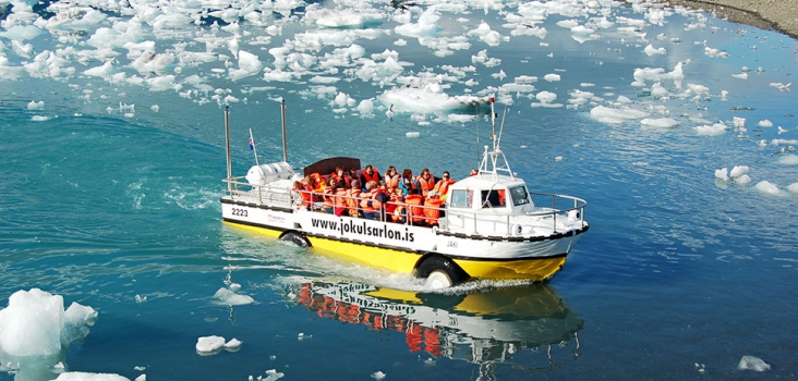 Glaciarlagoon in Iceland with iceblocks and a boat with many people from above